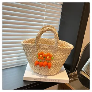 Detailed straw handbag featuring crochet orange flowers and carrot charms on a book