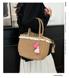 Dettaglio della borsa in paglia con frange bianche, nastro etnico e nappa rosa