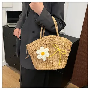 Détail du sac à bandoulière en paille avec marguerite tricotée blanche et nœud élégant