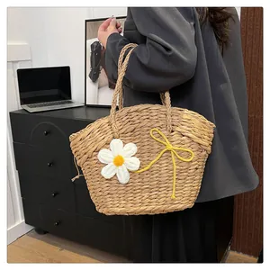 Détail du sac en paille avec marguerites tricotées et nœud décoratif jaune vif