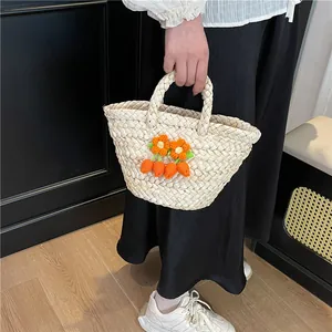 Minimalist cream woven straw handbag with orange crochet flowers and carrot decor