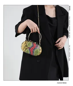 Detail of snake pattern texture on oval evening bag with golden handle and bow clasp