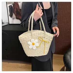 Détail du sac en paille avec fleurs de marguerite blanches et nœuds pour la plage