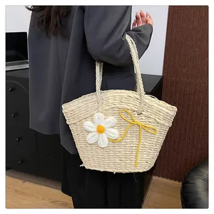 Détail du sac en paille tressée avec broderie florale et nœud sur un design en éventail
