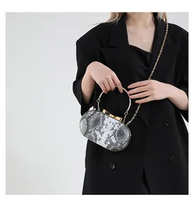 Detail of snake pattern evening bag with gold ring handle and chain strap on black blazer