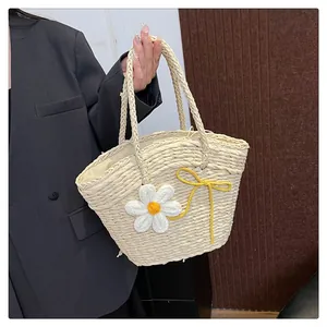 Détail d'un sac en paille tressé orné de marguerites blanches et d'un nœud jaune