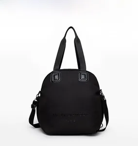 Front view of a minimalist black versatile handbag with adjustable straps and logo detail