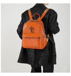 Detail of orange pebble leather backpack with silver studs and metal cross pendant