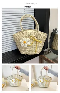 Détail d'un sac cabas en paille beige avec une fleur blanche en tricot pour la plage