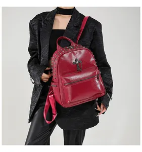 Detail of red faux leather backpack featuring silver studs and a metal cross charm
