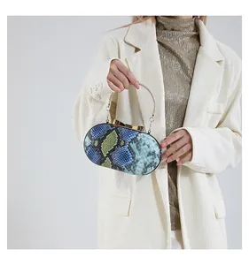 Detail view of snakeskin print clutch with gold metal handle and bow knot clasp