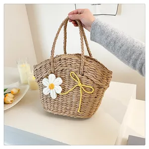 Détail du tissage d'un sac en paille avec marguerite au crochet et petit nœud jaune décoratif