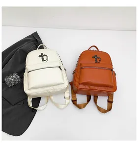 Detail view of mini backpacks with metal cross, chain, and side stud accents in two colors