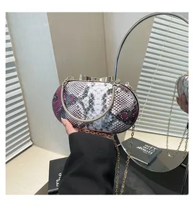 Detail of snake skin pattern evening bag with golden bow clasp and chain handle