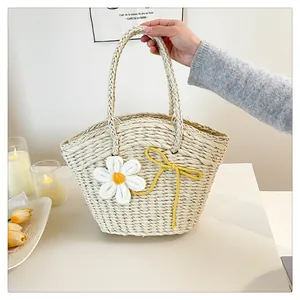 Détail du sac en paille tissé main avec marguerite blanche et nœud jaune d'été