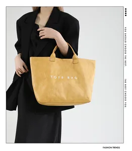 Detailed view of yellow tote bag with unique crinkle texture and white lettering logo