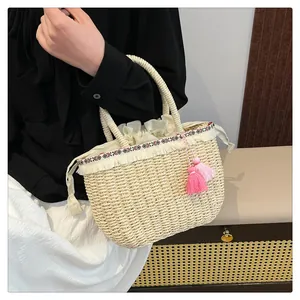 Dettaglio della borsa in paglia intrecciata con nappe rosa e frange con motivi etnici