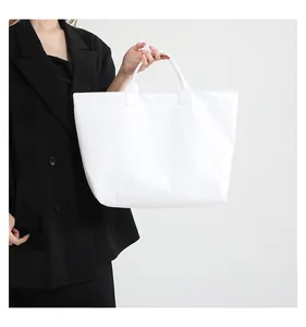 Minimalist white tote bag in wrinkled texture fabric styled with a black suit jacket