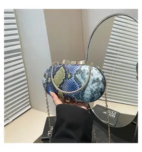 Detail of snake skin texture evening bag with gold bow clasp and ring handle