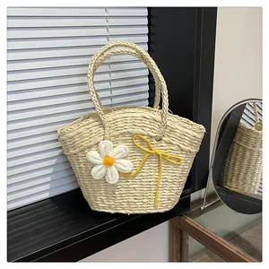 Détail d'un sac en paille fait main avec des fleurs en tricot et des anses tressées