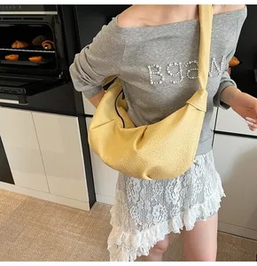Detail of yellow crescent shoulder bag with lychee texture and black zipper closure
