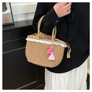 Dettaglio della borsa in paglia intrecciata con nappe a frange e nastro decorativo etnico