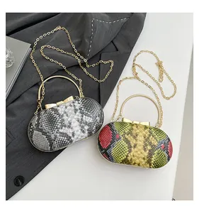 Detailed view of snake skin pattern evening clutches with gold ring handles and chain