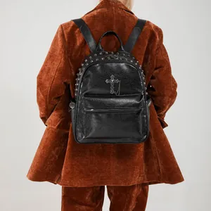 Chic black pebbled leather backpack with silver rivets and cross chain detail on model