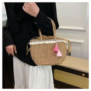 Dettaglio borsa di paglia con frange bianche, ricami etnici e nappe rosa