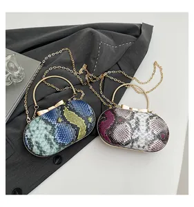 Detail of snakeskin textured clutch bags with gold metal handles and chain straps