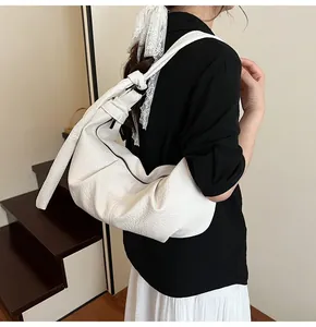 Detail of white pleated hobo bag with knotted shoulder strap and zipper closure