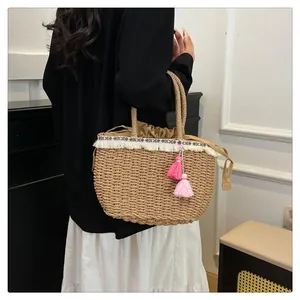 Dettaglio di borsa in paglia con nastro a motivo etnico e ciondoli con nappe boho
