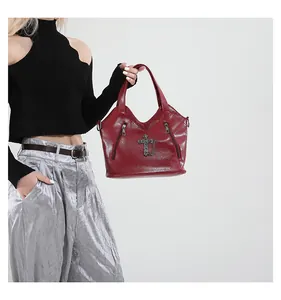 Detail of burgundy glossy faux leather biker bag with metal cross and zip accents