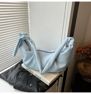 Detail of light blue textured leather shoulder bag with unique knotted wide strap and zipper