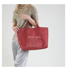 Detail of red oversized tote bag with wrinkled texture and white TOTE BAG print design