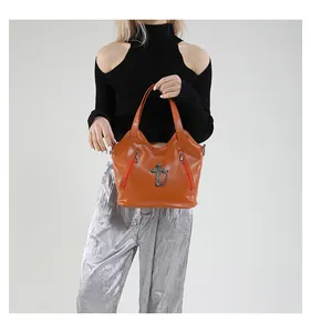 Detailed view of large orange cross handbag with textured leather and metal zippers