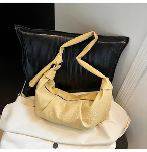 Close-up of the knotted shoulder strap and pleated texture of the yellow hobo bag