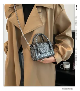 Mini silver crossbody bag with cross pattern and metal chain strap shown on a model