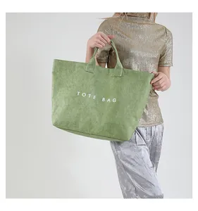 Fashion model styling a large green PVC tote bag with white lettering and vintage texture