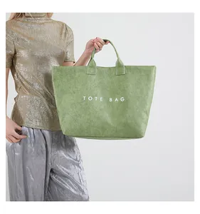 Detail of the grass green tote bag featuring a crinkled texture and bold white lettering