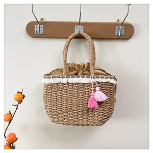 Dettaglio della borsa in paglia intrecciata con nappe boho e nastro decorativo