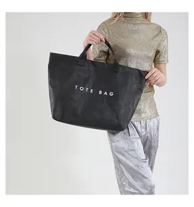 Detail of black printed tote bag featuring wrinkled texture and large white logo text