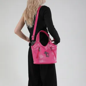 Hot pink faux leather crossbody bag with metallic cross pendant and side zippers