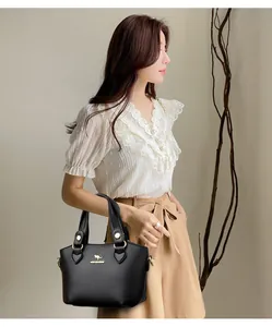 Détail d'un sac à main en cuir noir souple avec logo kangourou et finitions métalliques dorées