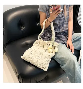 Detail of hollow floral crochet weave on cream straw tote bag with tulip pendant