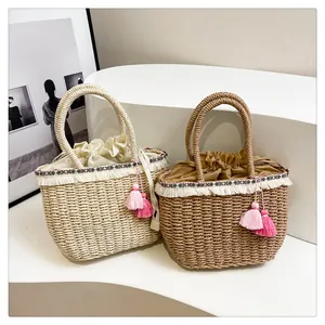 Dettaglio delle borse tote in paglia con frange bianche e nappe rosa decorative
