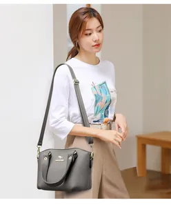 Détail du sac à main gris foncé avec logo kangourou doré et bandoulière réglable