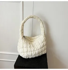 Primer plano de bolso acolchado crema con costuras cuadradas y detalle de cremallera metálica