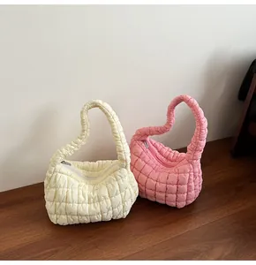 Primer plano de bolsos acolchados en crema y rosa con textura suave de efecto burbuja