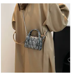 Detail of gothic silver crossbody bag with embossed crosses and silver chain strap